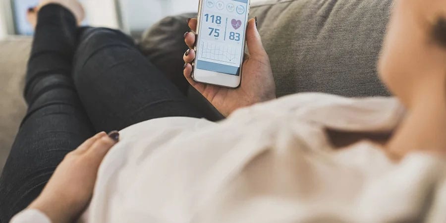 Pregnant woman reviewing medical data on smart device